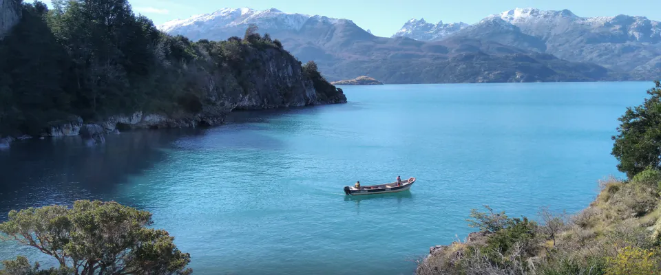 Lancha navegando el lago General Carrera con montañas nevadas