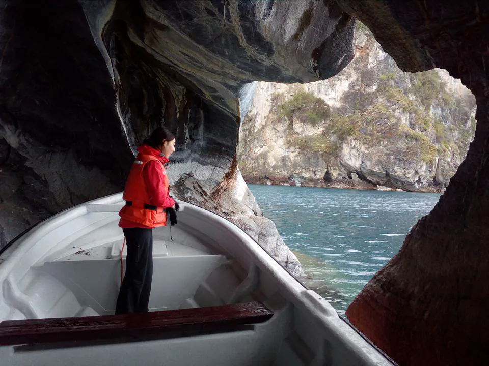 Pasajera en la proa de la lancha dentro de una caverna de mármol